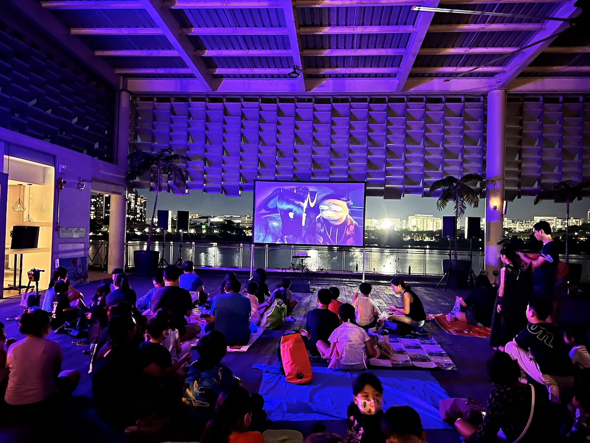 Movie Screening: 6 Easy Ways to Plan Better Seating 12 Families watching a movie from mats in a covered waterfront space